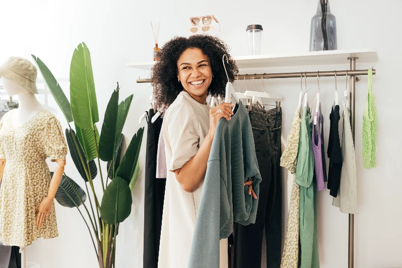 Laughing woman choosing sweatshirt in a store